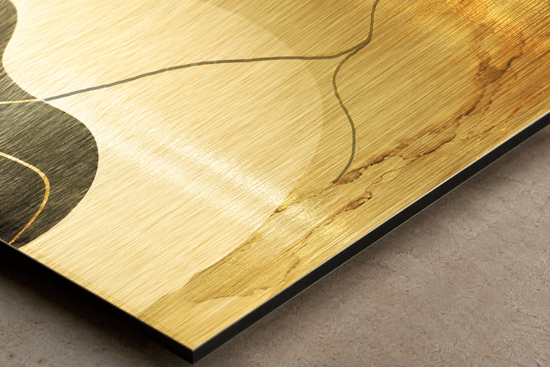 Close-up detail of brushed gold dibond showing horizontal texture lines with abstract artwork and black edge profile