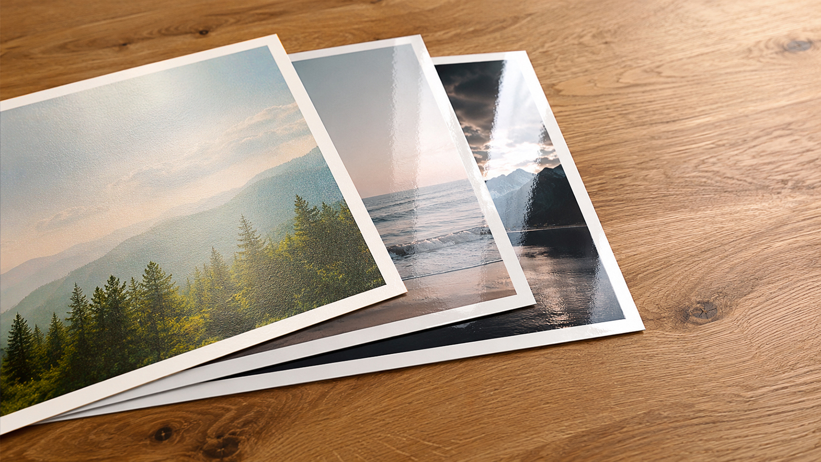 Three glossy photo prints with vibrant landscape photography: forest mountains, ocean sunset, and dramatic sky