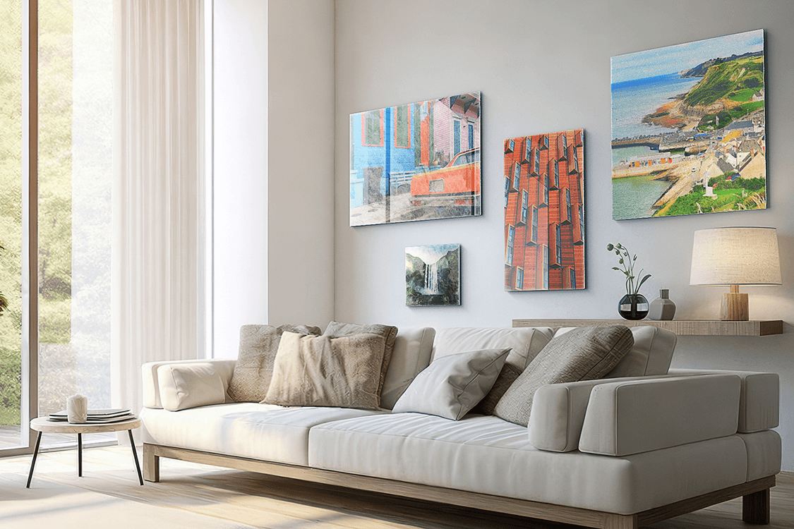 Asymmetric gallery wall of four Acrylux Classic acrylic prints — travel and architecture photos — above a cream sofa in a bright, modern living room