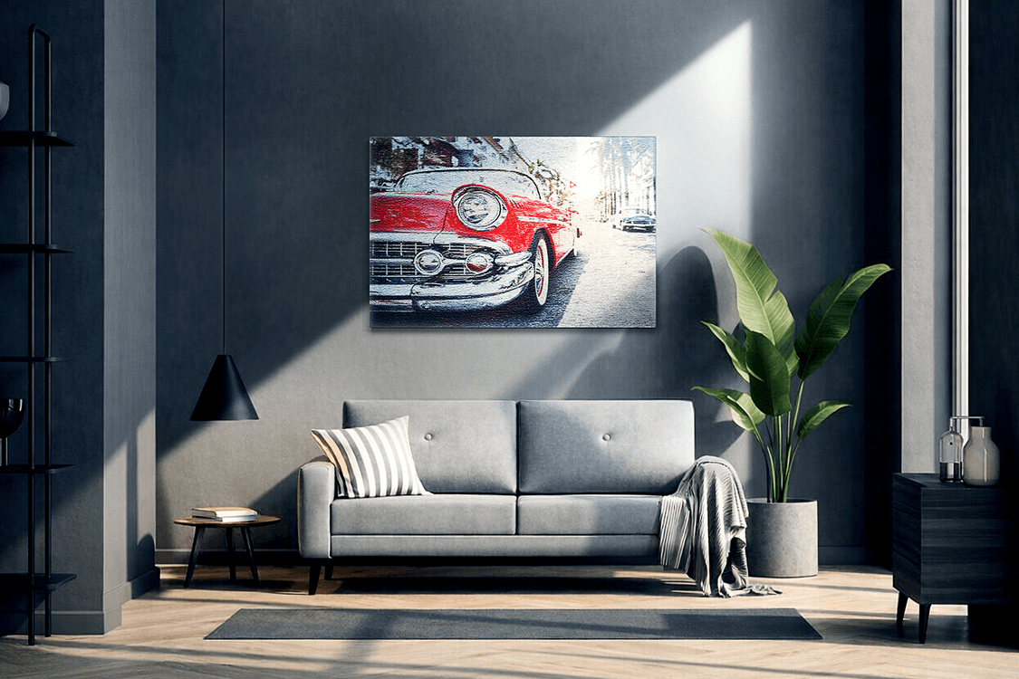 Red vintage car photo on Acrylux Metallic acrylic print hanging above a grey sofa in a dark modern living room