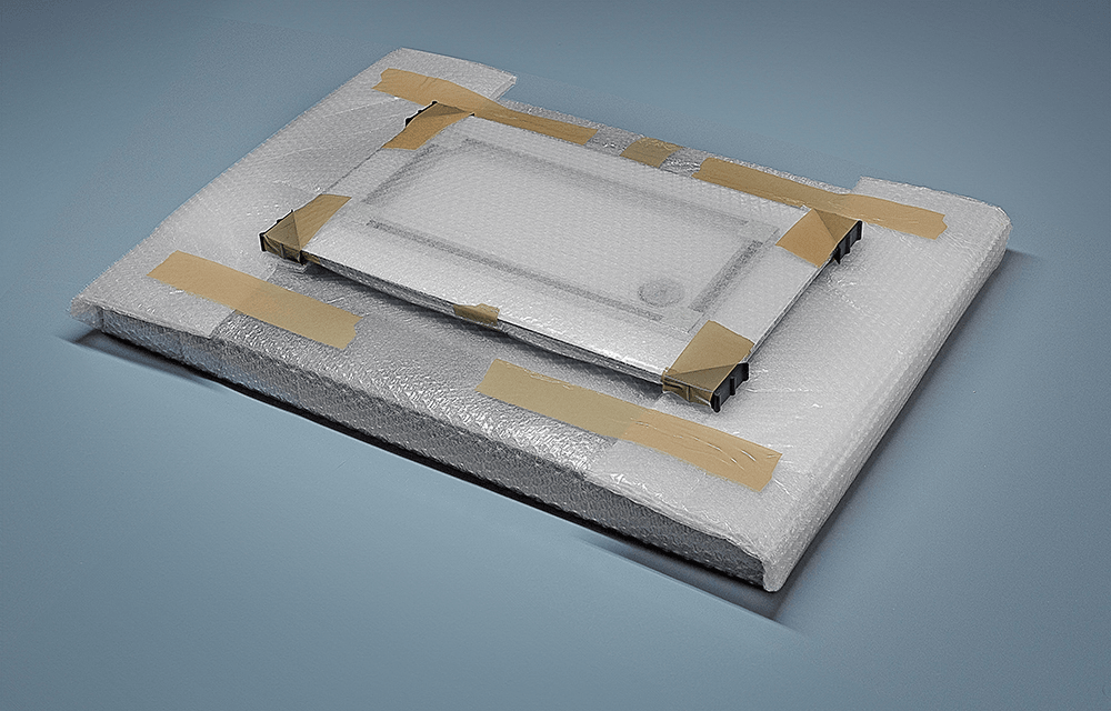 Photo print wrapped in protective bubble foam with cardboard corner protectors, ready for shipping