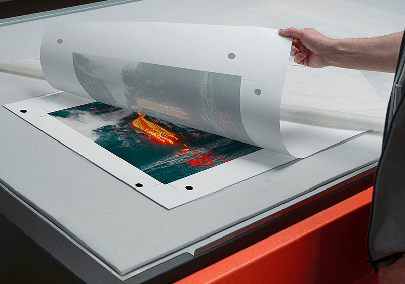 Technician lifting a sublimation transfer sheet from a ChromaLuxe aluminium panel on a heat press