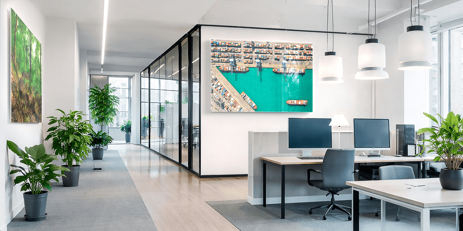 Large photo behind plexiglass of an aerial harbour view displayed in a modern white office with plants and desks
