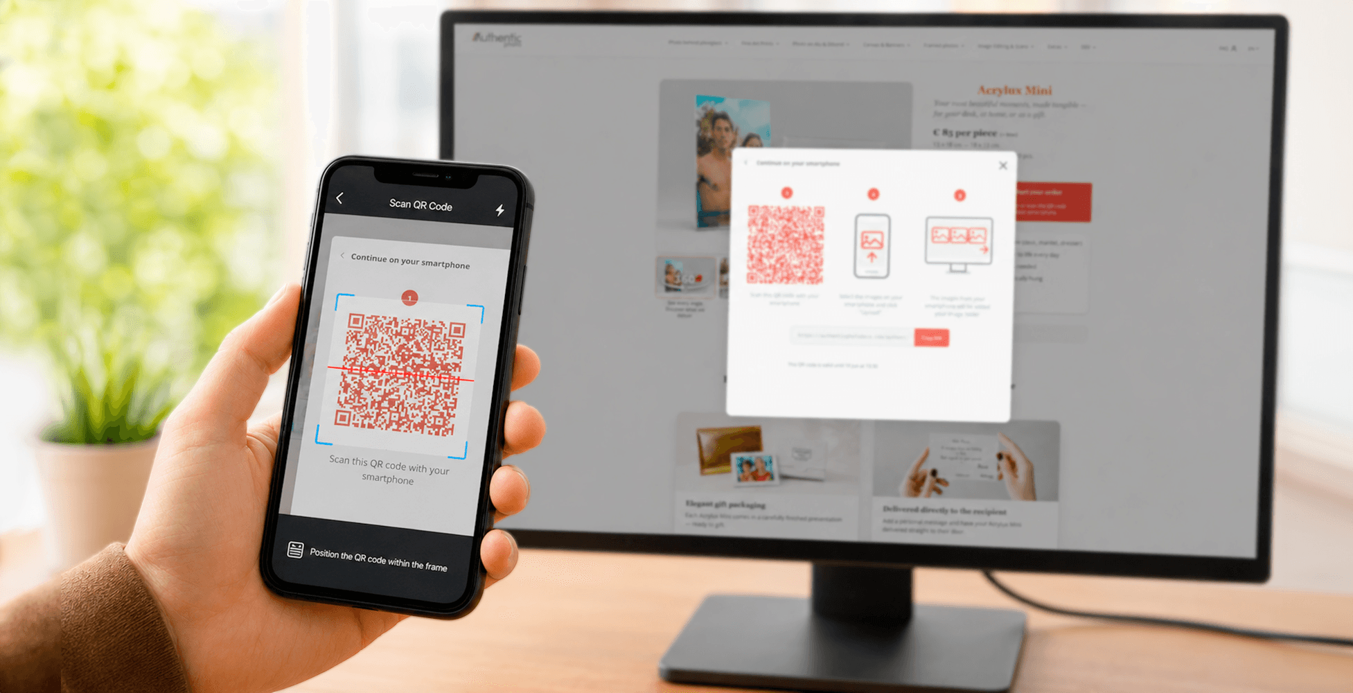 Hand holding smartphone scanning QR code displayed on desktop monitor showing Acrylux Mini order interface