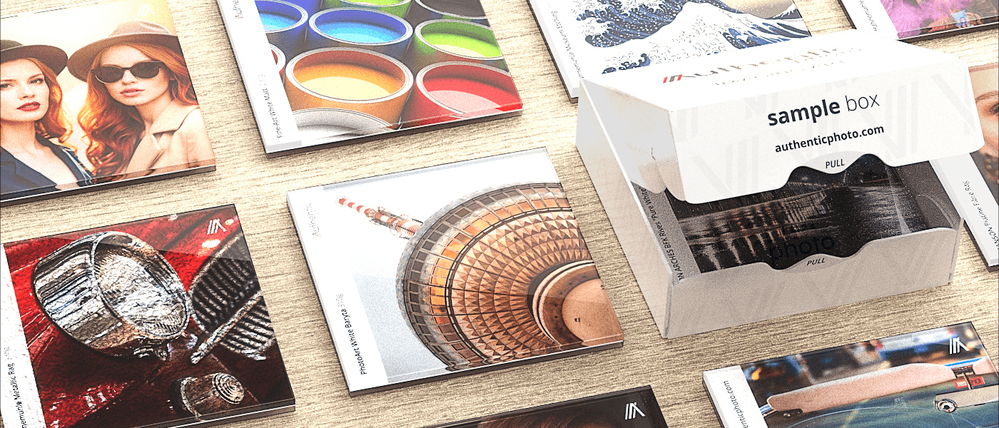 Plexiglass photo print sample set with branded box and various mounted samples on a wooden surface